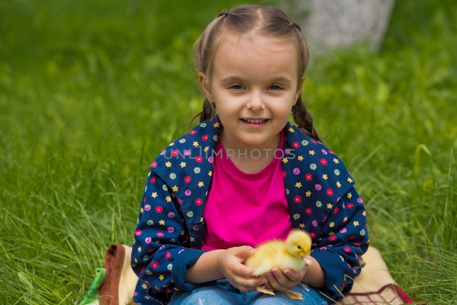 Cute happy little girl with of small duckling in the garden. Little girl holding a duckling in her hands.