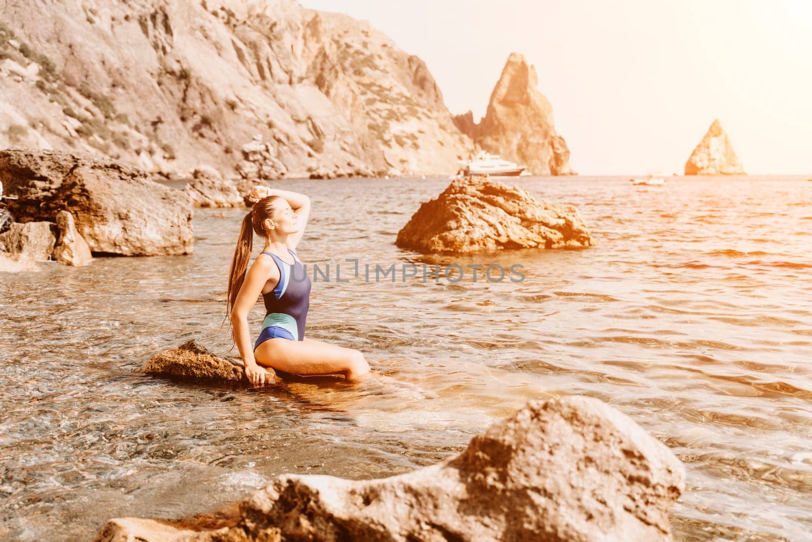 Woman travel summer sea. A happy tourist in a blue bikini enjoying the scenic view of the sea and volcanic mountains while taking pictures to capture the memories of her travel adventure. by Matiunina