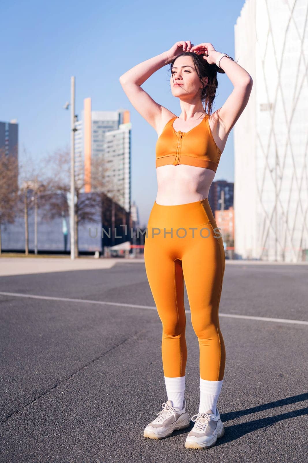 vertical photo of a beautiful caucasian woman in sportswear preparing to running outdoors, concept of active lifestyle and urban sport