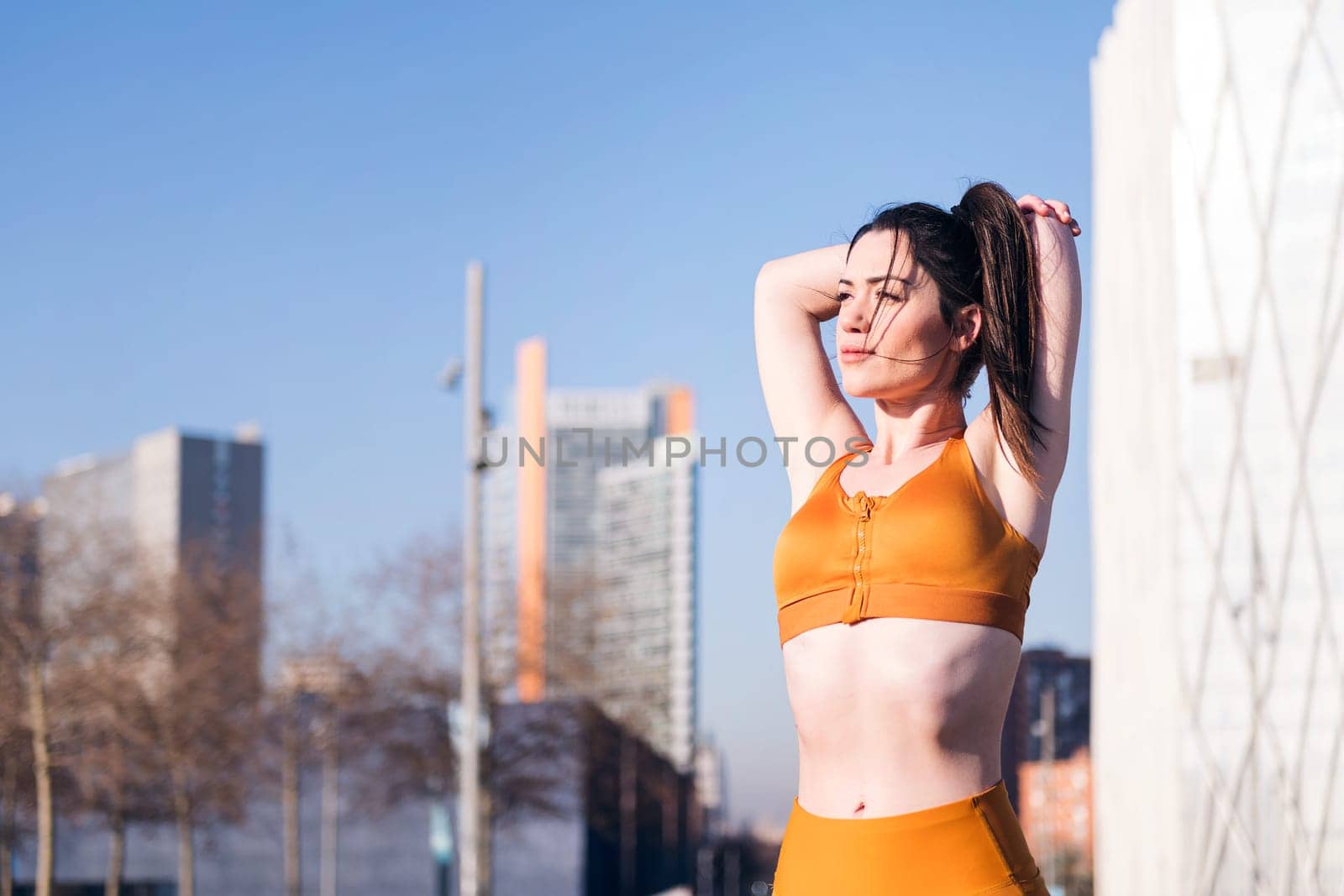 caucasian fit woman stretching arms in an urban park, concept of health and sportive lifestyle, copy space for text