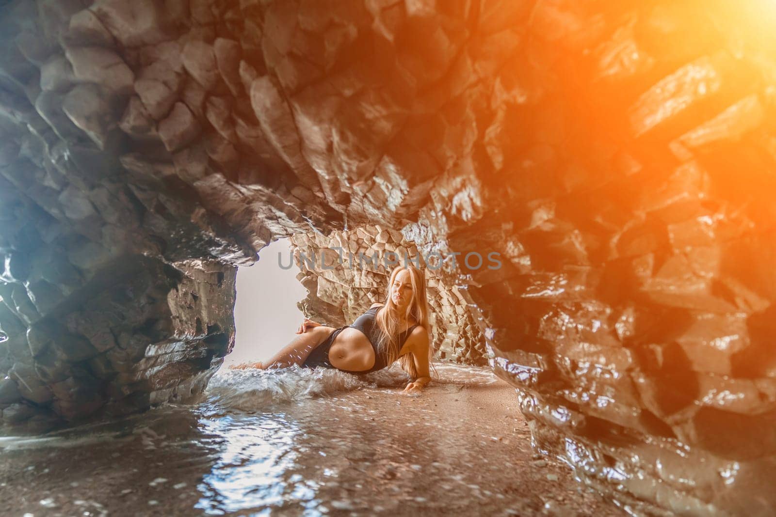 Woman swimsuit sea. Attractive blonde woman in a black swimsuit enjoying the sea air on the seashore around the rocks. Travel and vacation concept