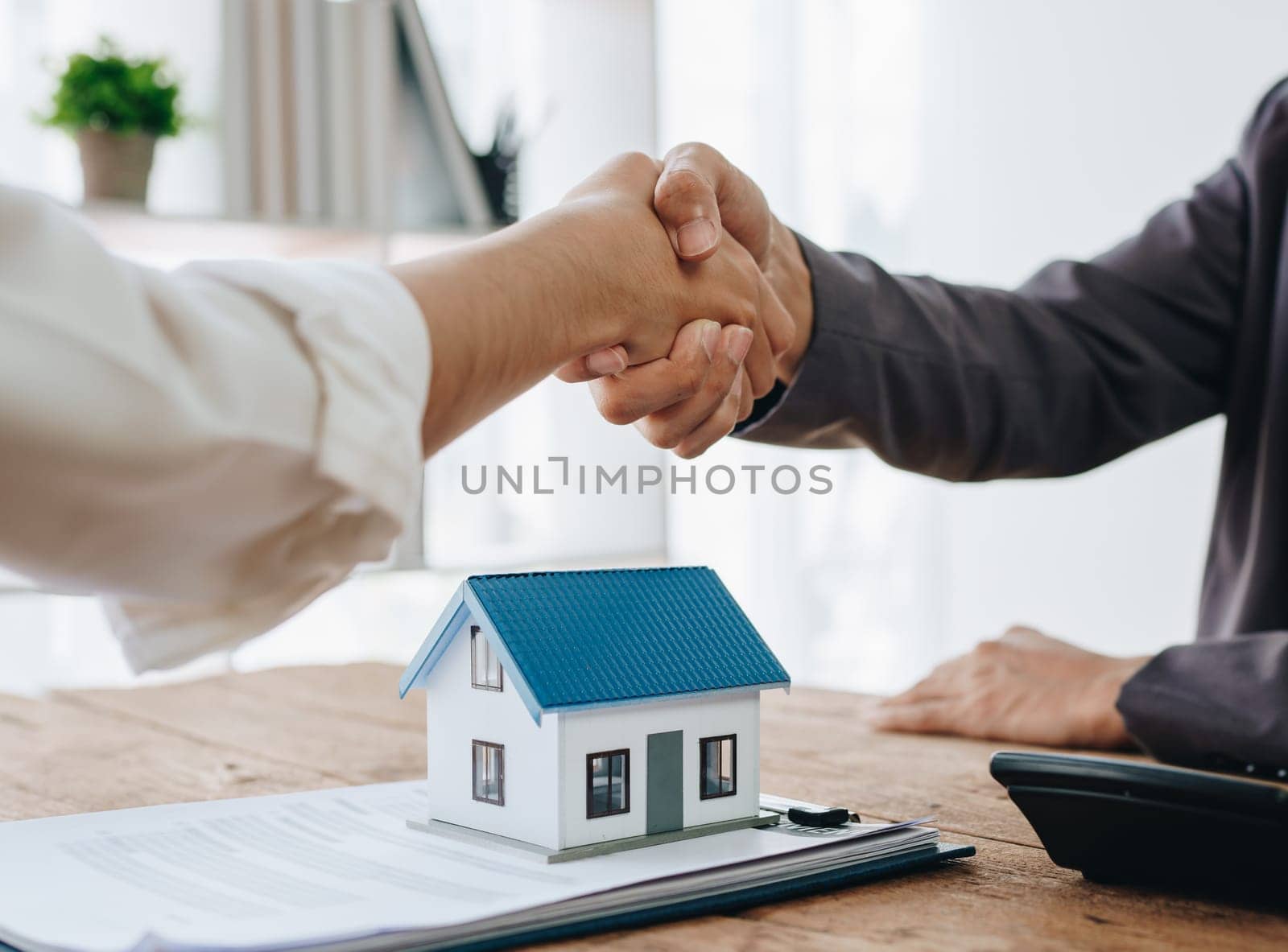 The bank's Mortgage Officers shake hands with customers to congratulate them after signing a housing investment loan agreement by Manastrong