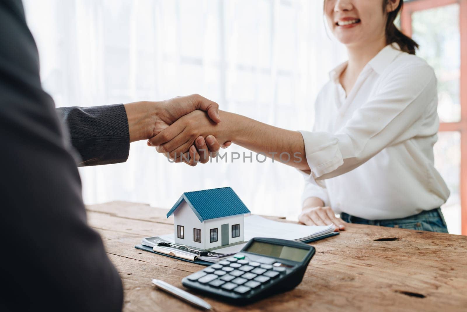 The bank's Mortgage Officers shake hands with customers to congratulate them after signing a housing investment loan agreement by Manastrong