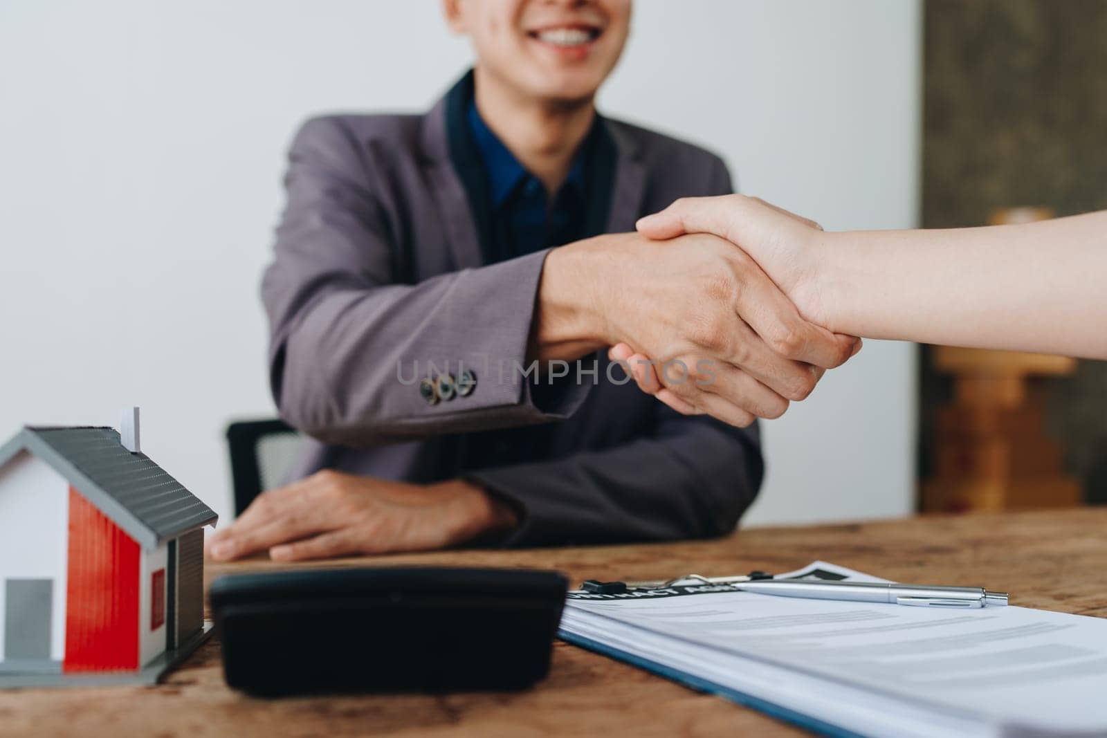 The bank's Mortgage Officers shake hands with customers to congratulate them after signing a housing investment loan agreement by Manastrong