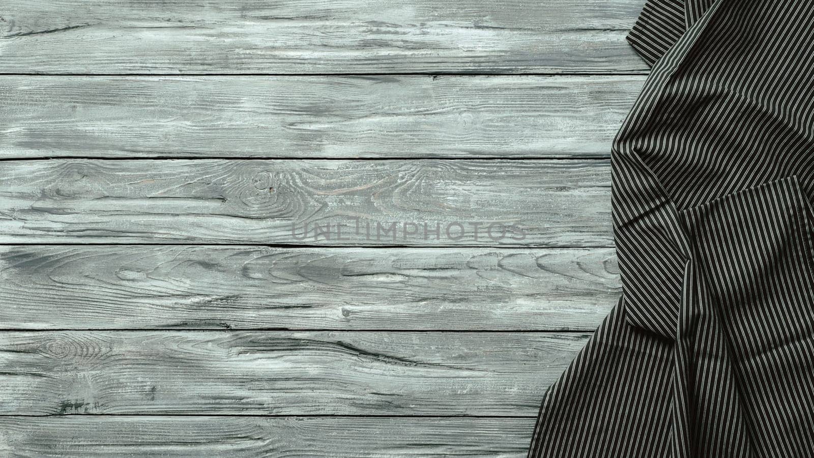 Gray wooden table with balck and white dark linen kitchen towel or textile napkin flat lay. Dark tablecloth on old gray wood tabletop. Copy space for text. Can use as mock up for design.