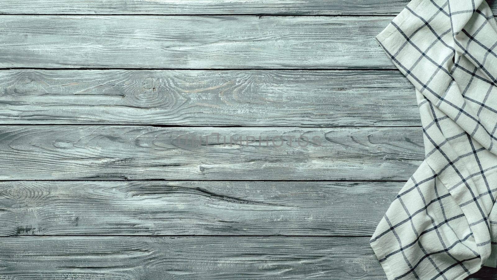 Gray wooden table with linen kitchen towel or textile napkin flat lay. Blue tablecloth on old gray wood tabletop. Copy space for text. Can use as mock up for design.