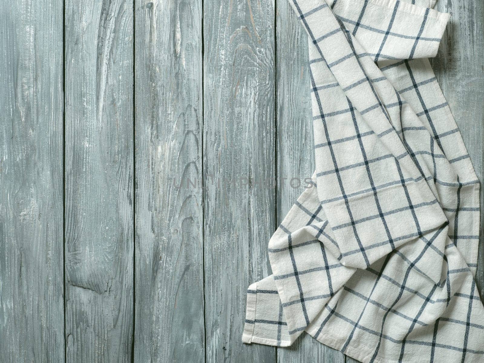 Gray wooden table with linen kitchen towel or textile napkin flat lay. Blue tablecloth on old gray wood tabletop. Copy space for text. Can use as mock up for design.