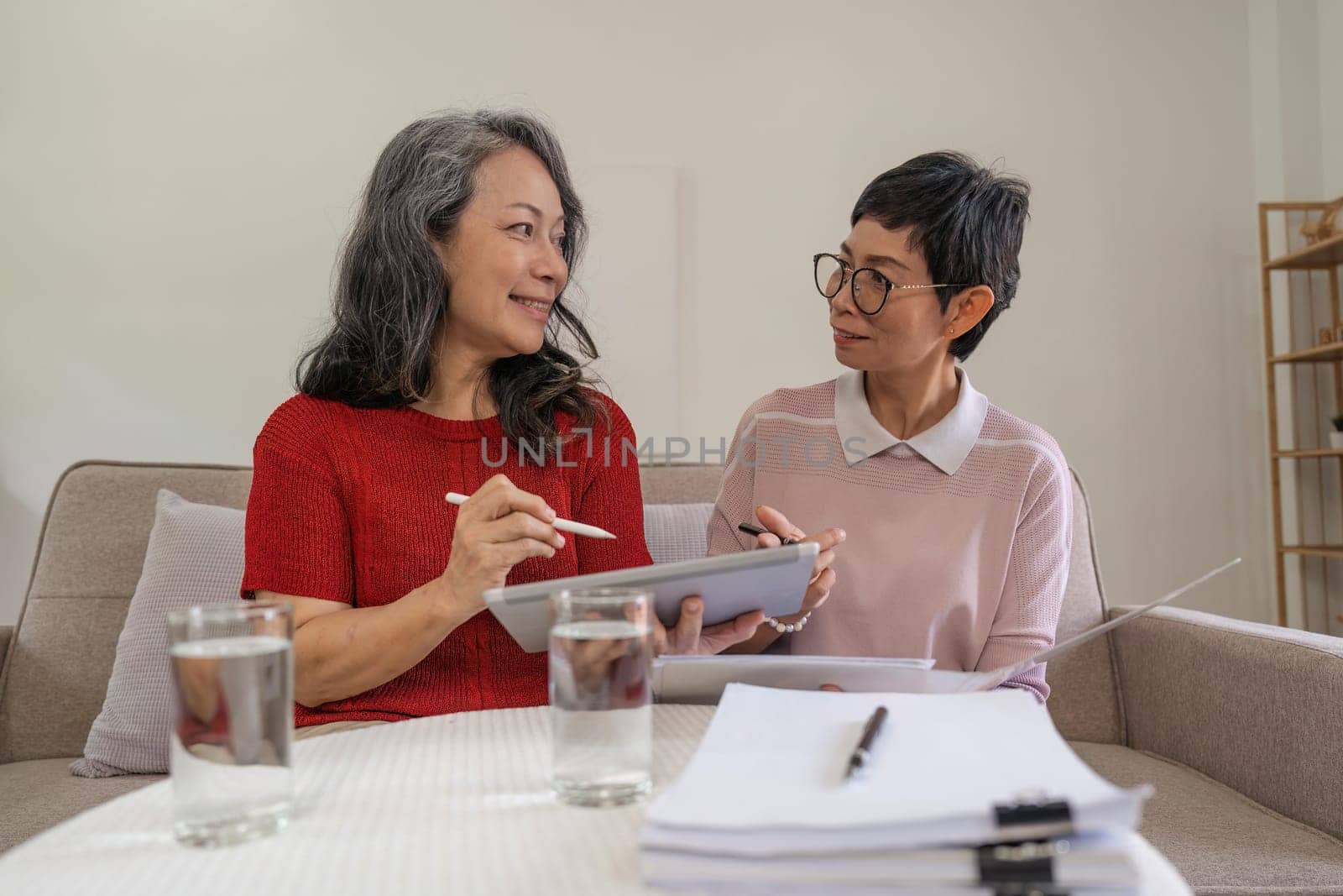 Portrait of two friend happy senior adult elderly asia women smiling and working with laptop computer at home.