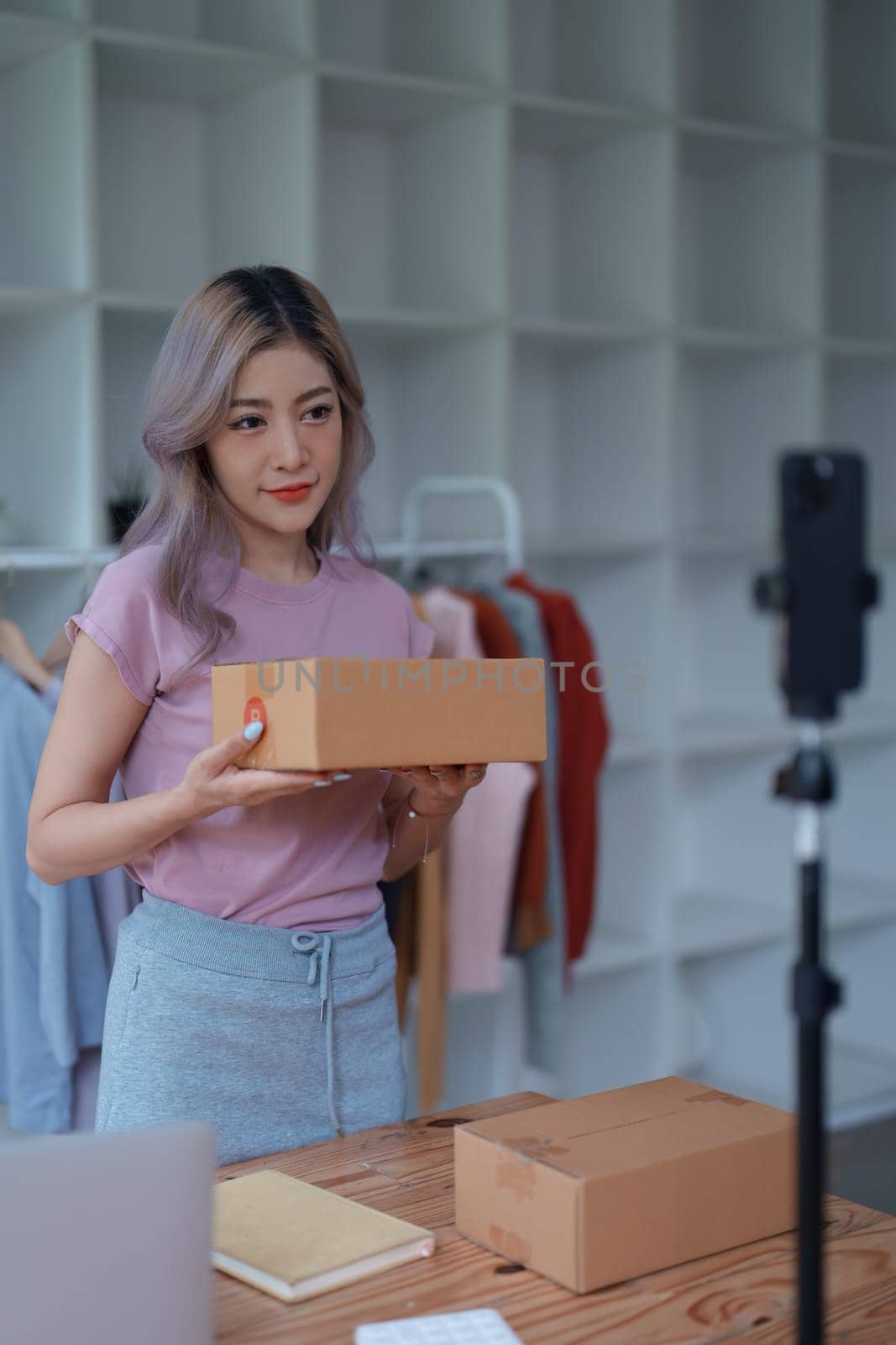 Beautiful Asian woman, blogger, blog, presenting fashion clothes, live video, social media, record her, sell online via digital cameras, sme or small business ecommerce concepts by Manastrong