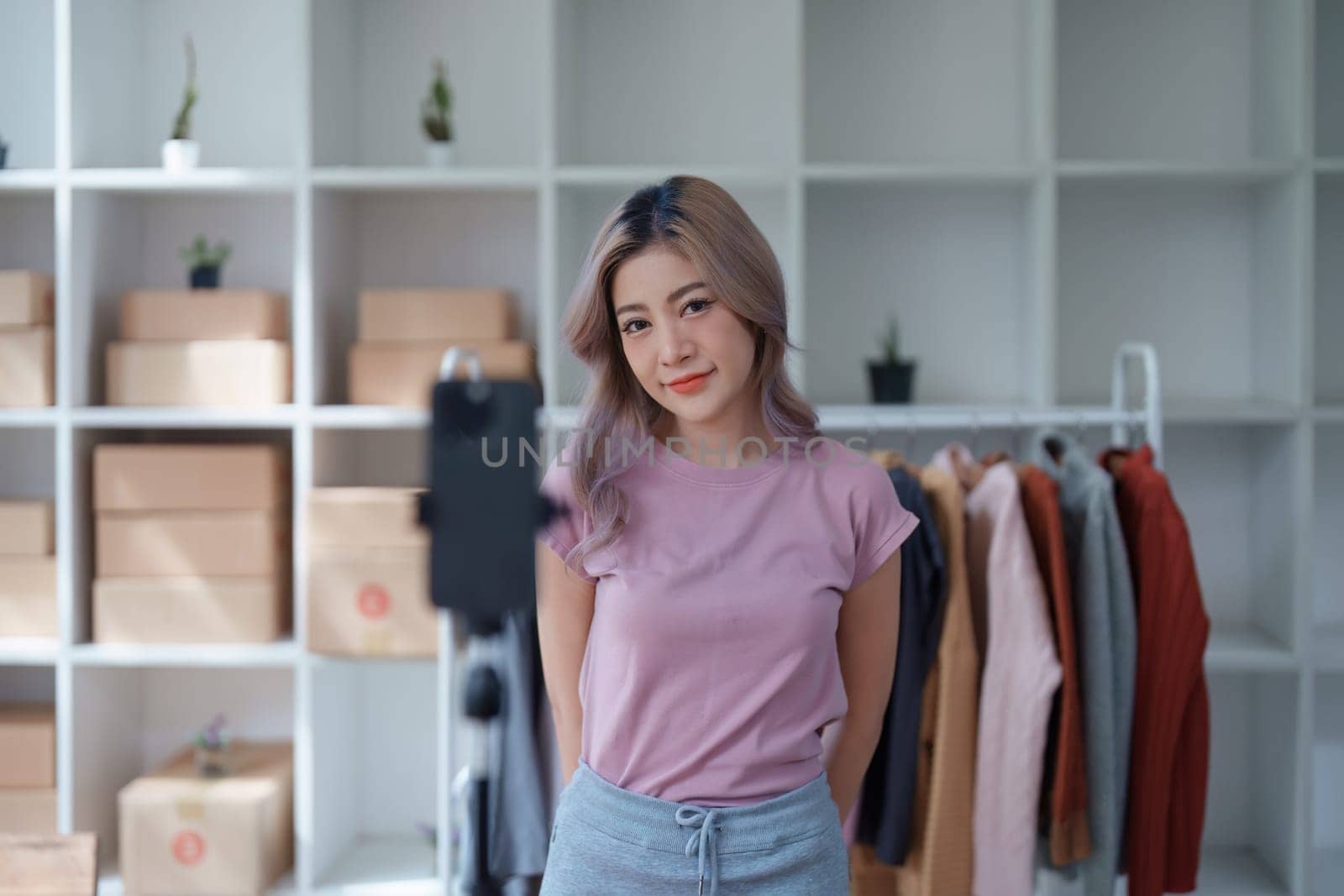 Beautiful Asian woman, blogger, blog, presenting fashion clothes, live video, social media, record her, sell online via digital cameras, sme or small business ecommerce concepts.