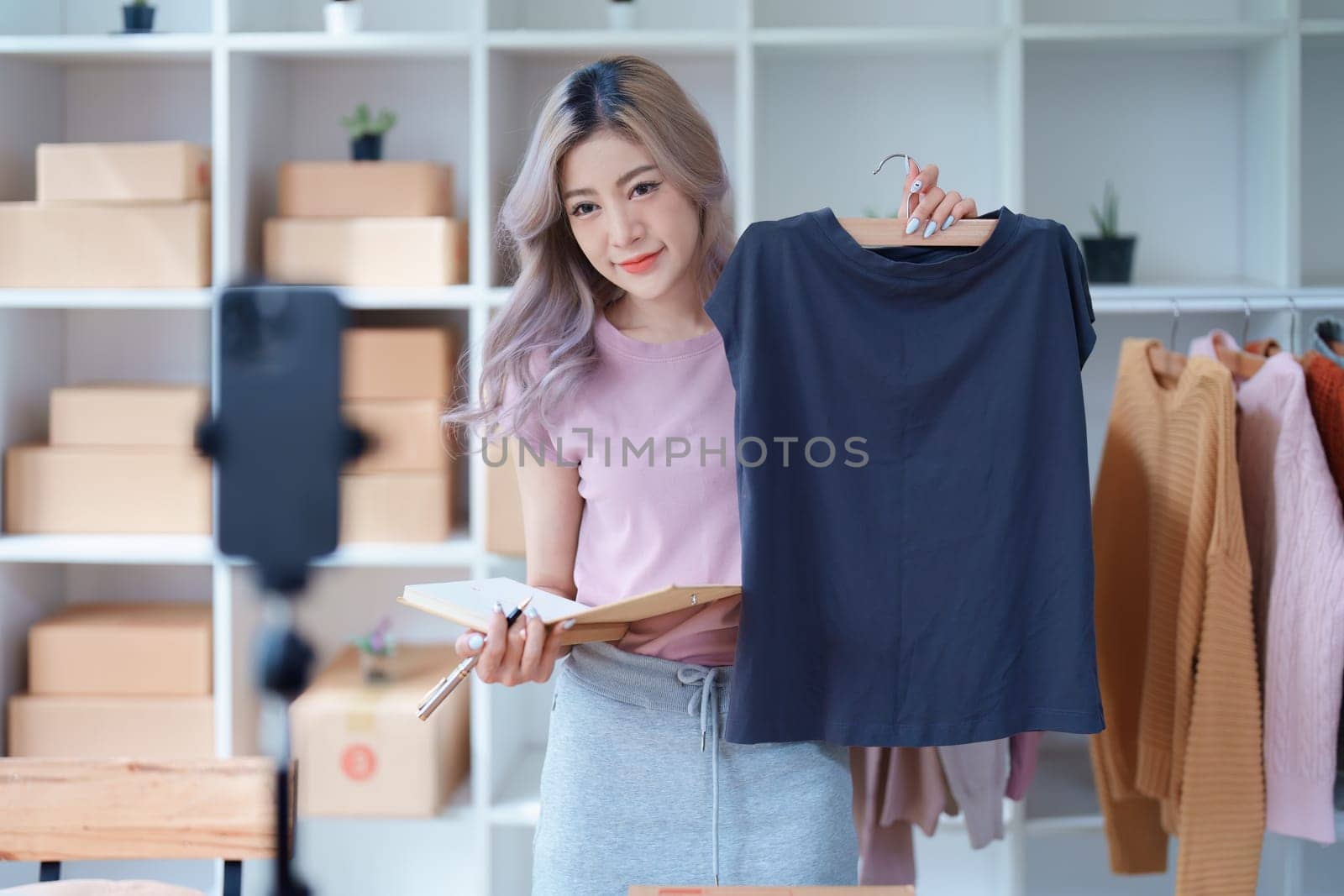 Beautiful Asian woman, blogger, blog, presenting fashion clothes, live video, social media, record her, sell online via digital cameras, sme or small business ecommerce concepts.
