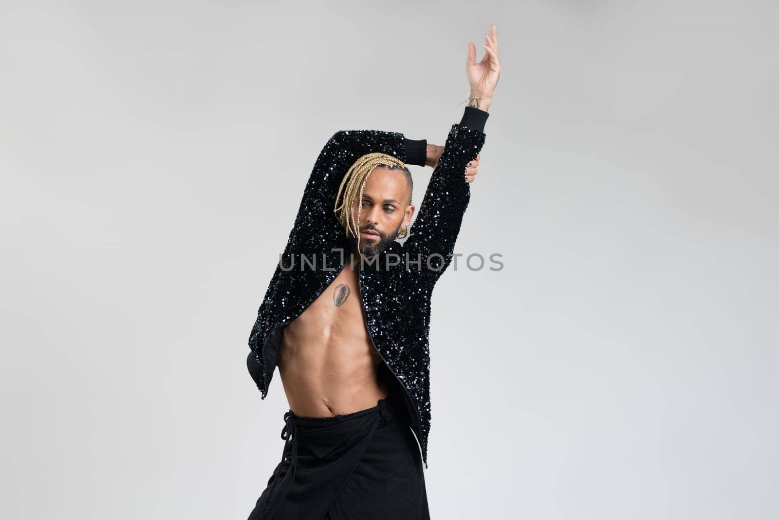 Man wearing women clothing dancing. Afro-american homosexual male wearing black skirt and jacket with sequins posing in photo studio on white background. Bearded gay with make up