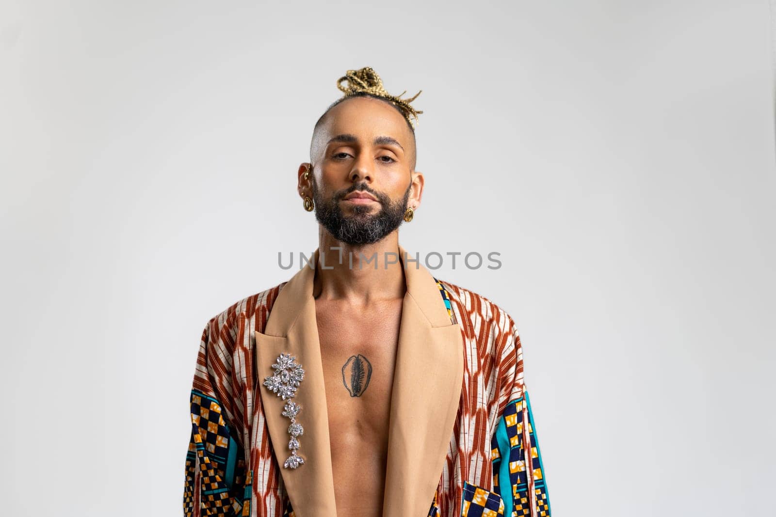 Gay man standing confidently isolated on white background, dressed vibrant, colorful jacket. Serious face looking camera, bold masculinity and self-assurance.