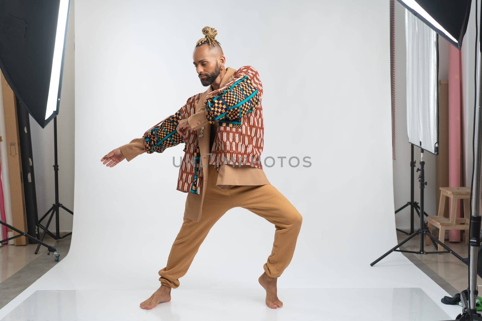 Full length gay man wearing stylish clothing dancing. Brazilian homosexual male posing in photo studio on white background. Bearded gay man