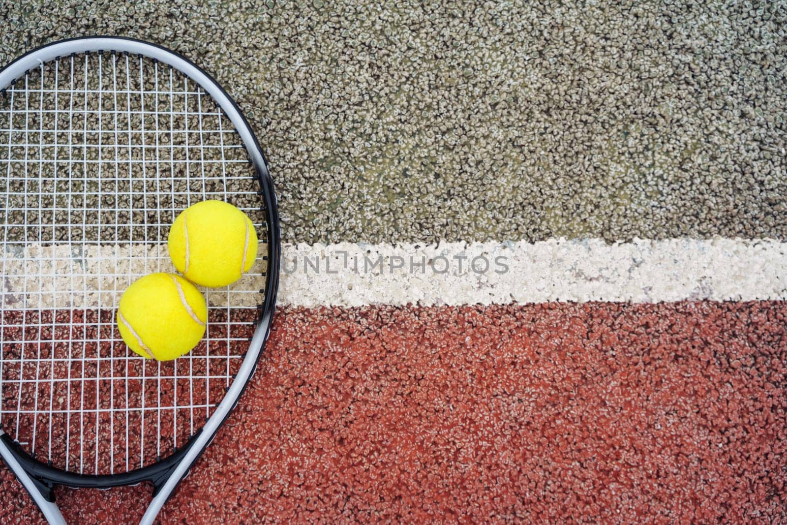 Closeup top view on yellow tennis balls and racket racquet lying on acrylic tennis hard court surface with empty blank copy space.