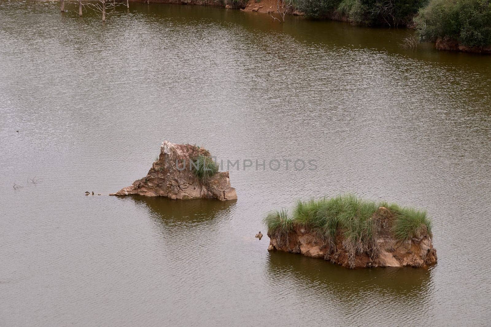 Two large rocks emerging in a lake by raul_ruiz