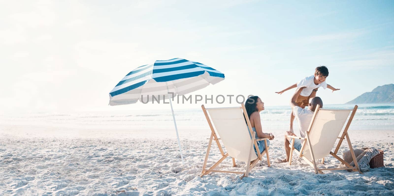 Beach, travel and family relaxing while on a vacation, adventure or weekend trip for summer. Freedom, bonding and father flying his boy child sitting by the ocean with his wife on a tropical holiday