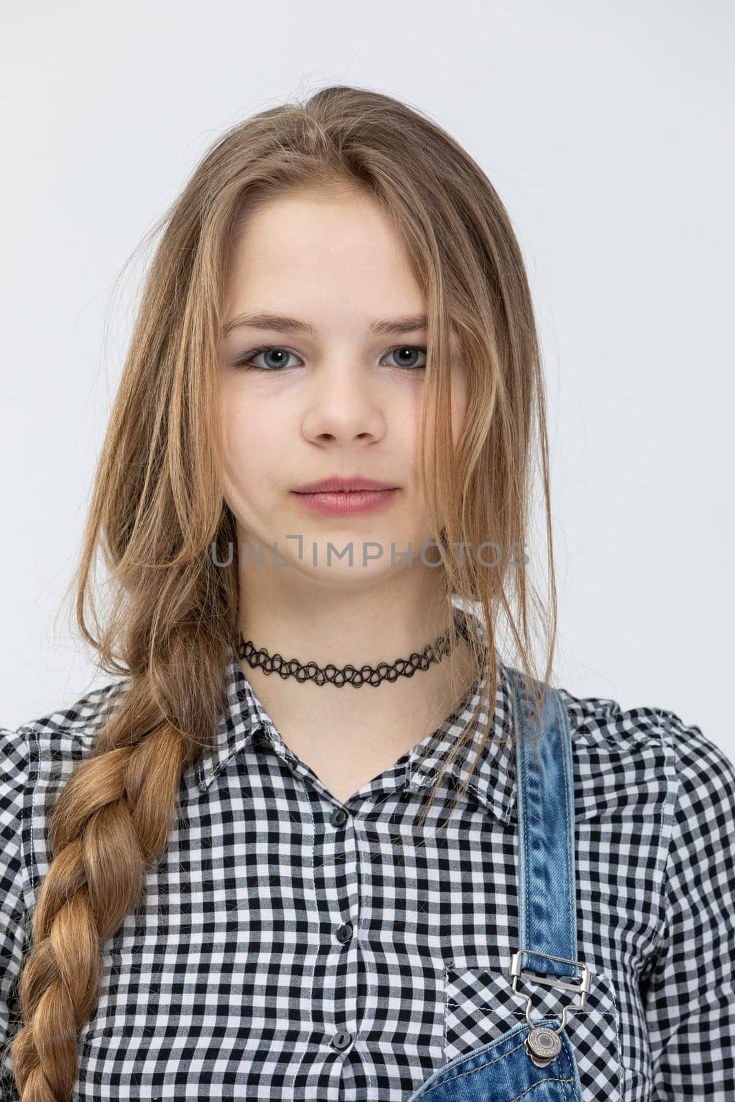 A young girl poses for a photo. Bust of girl seen in front. Girl wearing a fine checkered shirt. A woman combed into a braid. A brown-haired woman poses for a photo shoot.