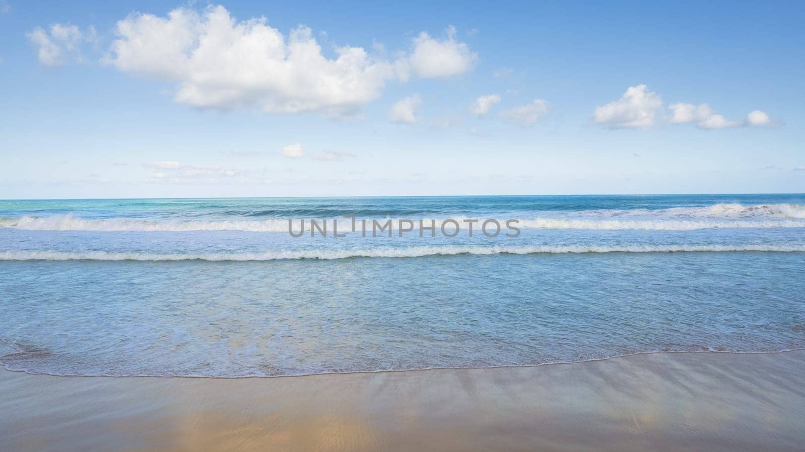 Golden sand and blue ocean water with white clouds by Passcal