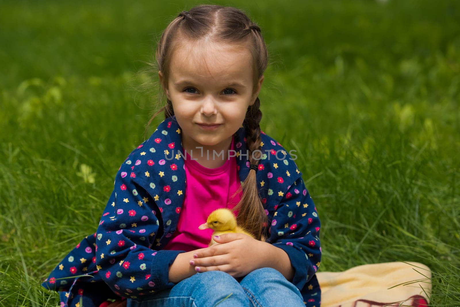 Cute happy little girl with of small duckling in the garden. Little girl holding a duckling in her hands.