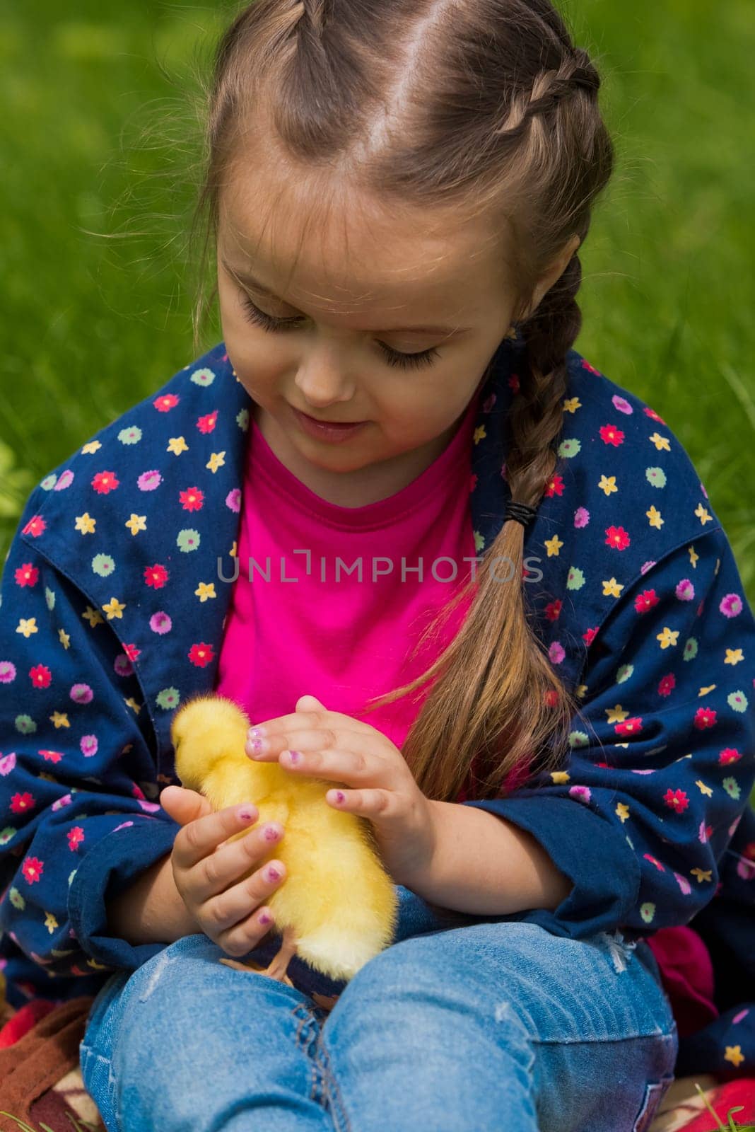 Cute happy little girl with of small duckling in the garden. Nature background.