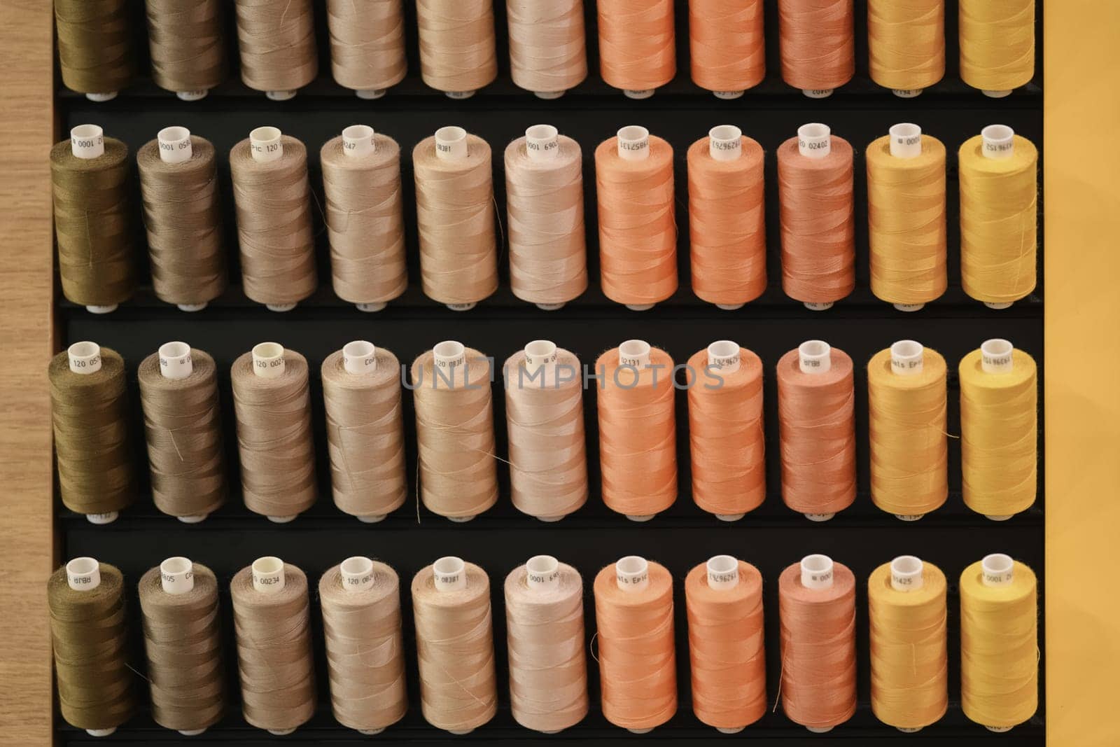 A row of multi-colored thread spools in brown orange yellow tones