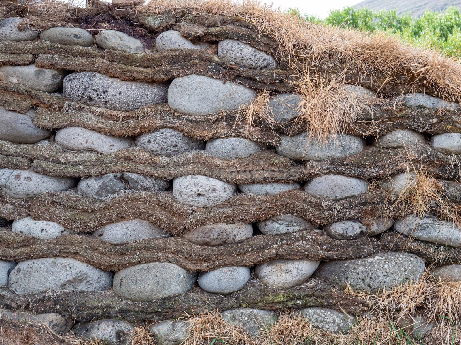 Image of Traditional Icelandic turf wall built over stones and made of clamped blocks with strips between the layers.