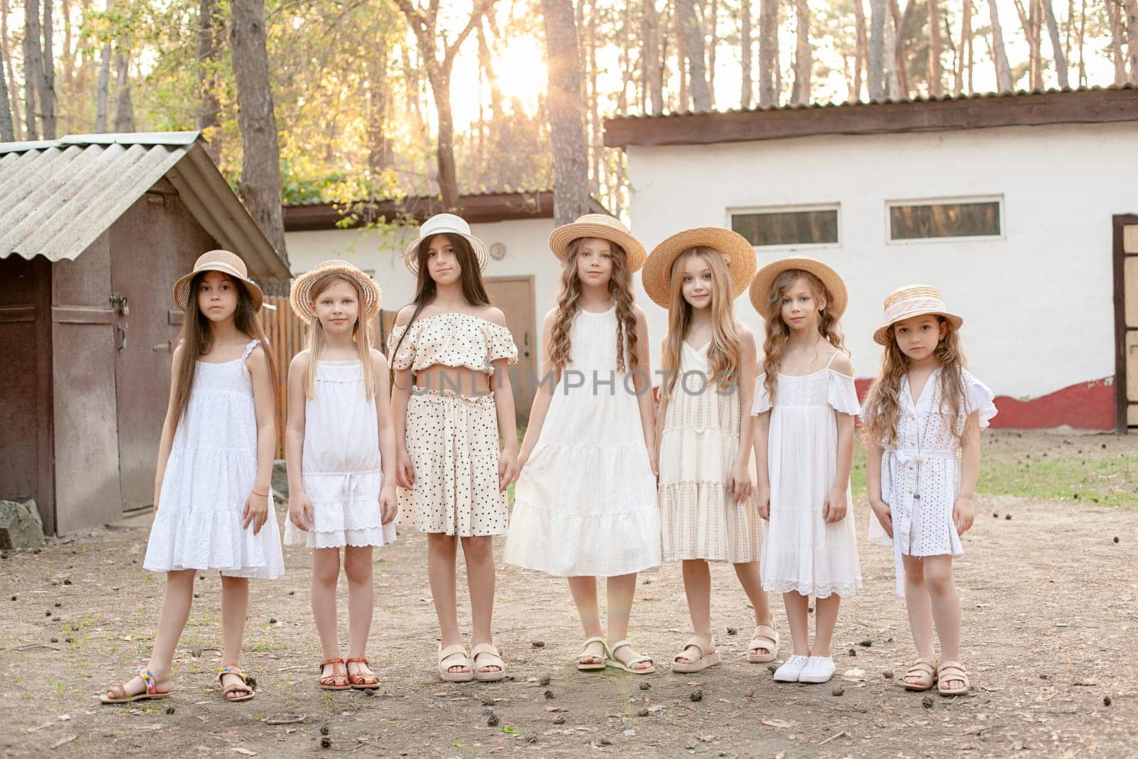 Preteen girls in light dresses standing in backyard of country house in forest by nazarovsergey