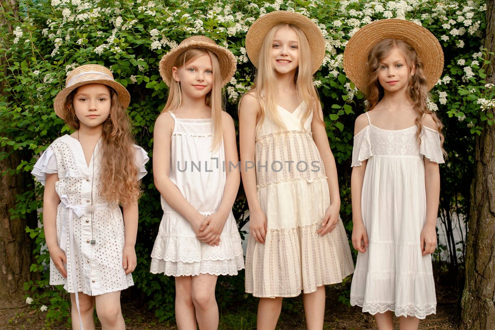 Smiling tween girls standing in summer park near green blooming bush by nazarovsergey