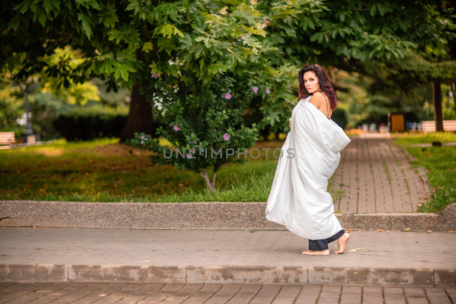Woman city blanket. Morning in the big city. A blonde woman in a white blanket is enjoying in the city center. Photographed for social media.