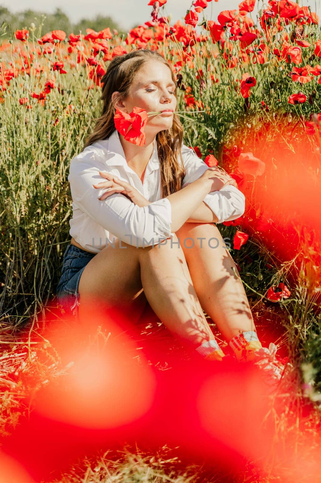 Woman poppies field. Happy woman is resting in the rays of the sun sitting in the poppy field. by Matiunina