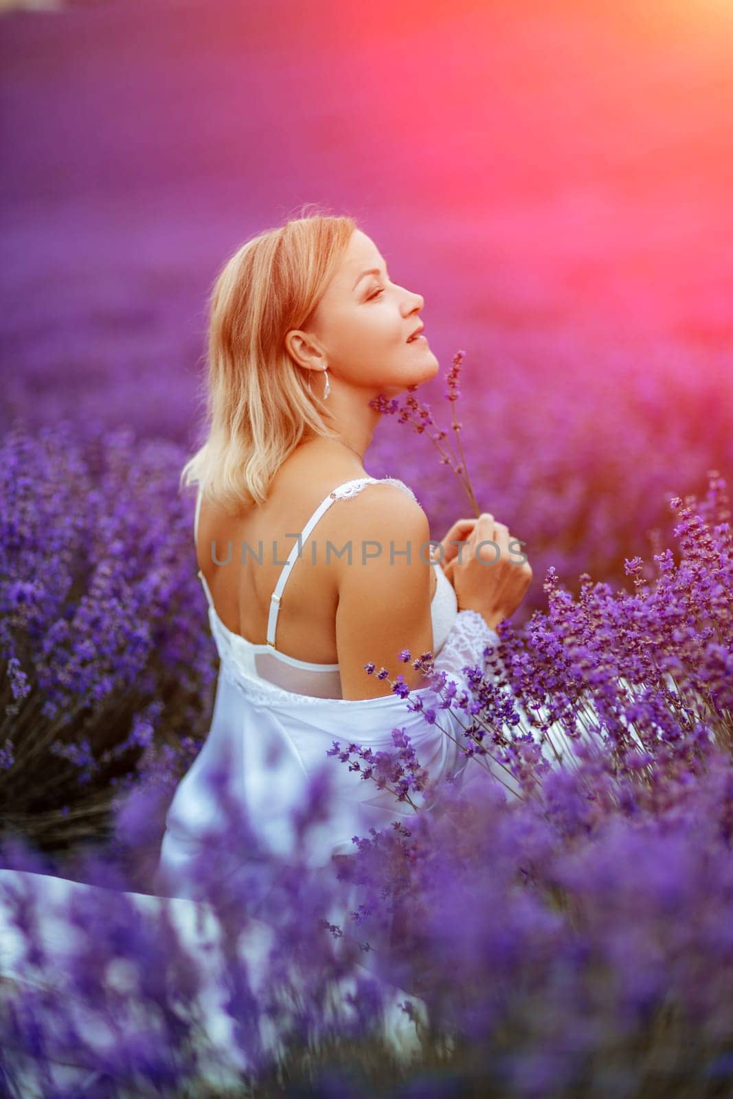 Woman lavender field. A middle-aged woman sits in a lavender field and enjoys aromatherapy. Aromatherapy concept, lavender oil, photo session in lavender by Matiunina