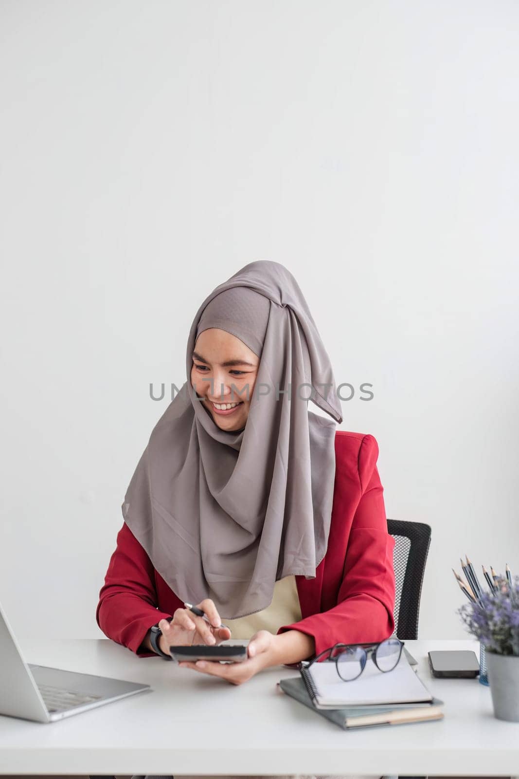 muslim businesswoman using calculator and laptop for do math finance on wooden desk in office and business working background, tax, accounting, statistics and analytic research concept