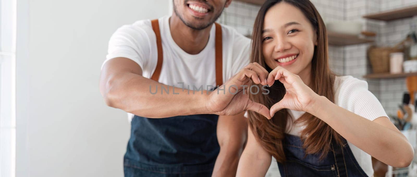 Love, a couple and heart hand sign man and woman together. Marriage, heart hands and relationship with support and trust in kitchen by nateemee