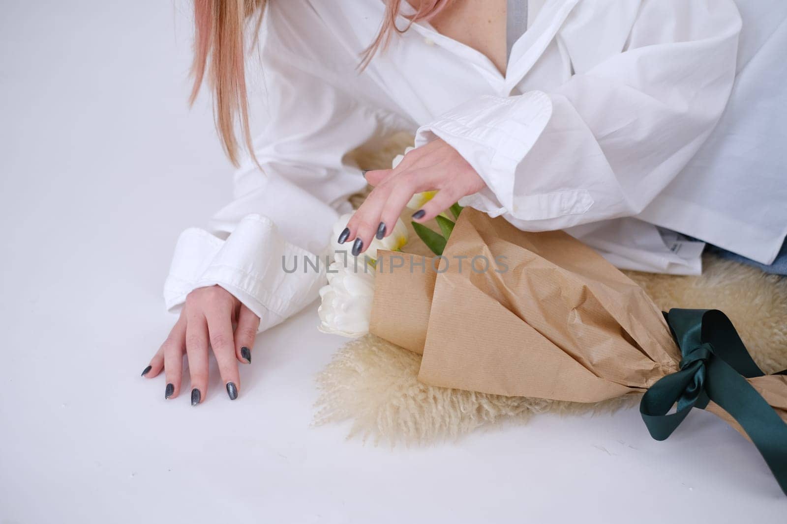 Woman in white lying next to a bouquet of white tulips. Feminine. White shirt. Gift concept for woman, love, birthday, 8 March, mother day. White background