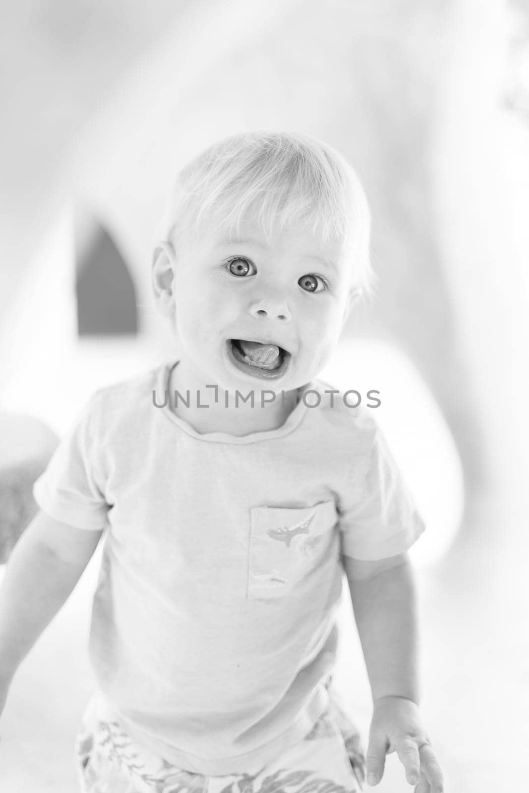 Black and white portrait of cute little infant baby boy child playing on outdoor playground. Toddler plays on school or kindergarten yard