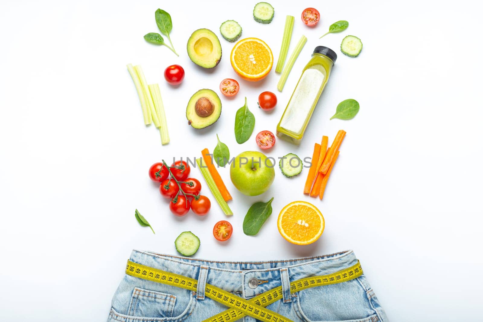 Fresh fruit, vegetables, smoothie falling into jeans and yellow measuring tape instead of belt on white background. Concept of healthy food for weight loss, detox, diet, healthy clean nutrition by its_al_dente