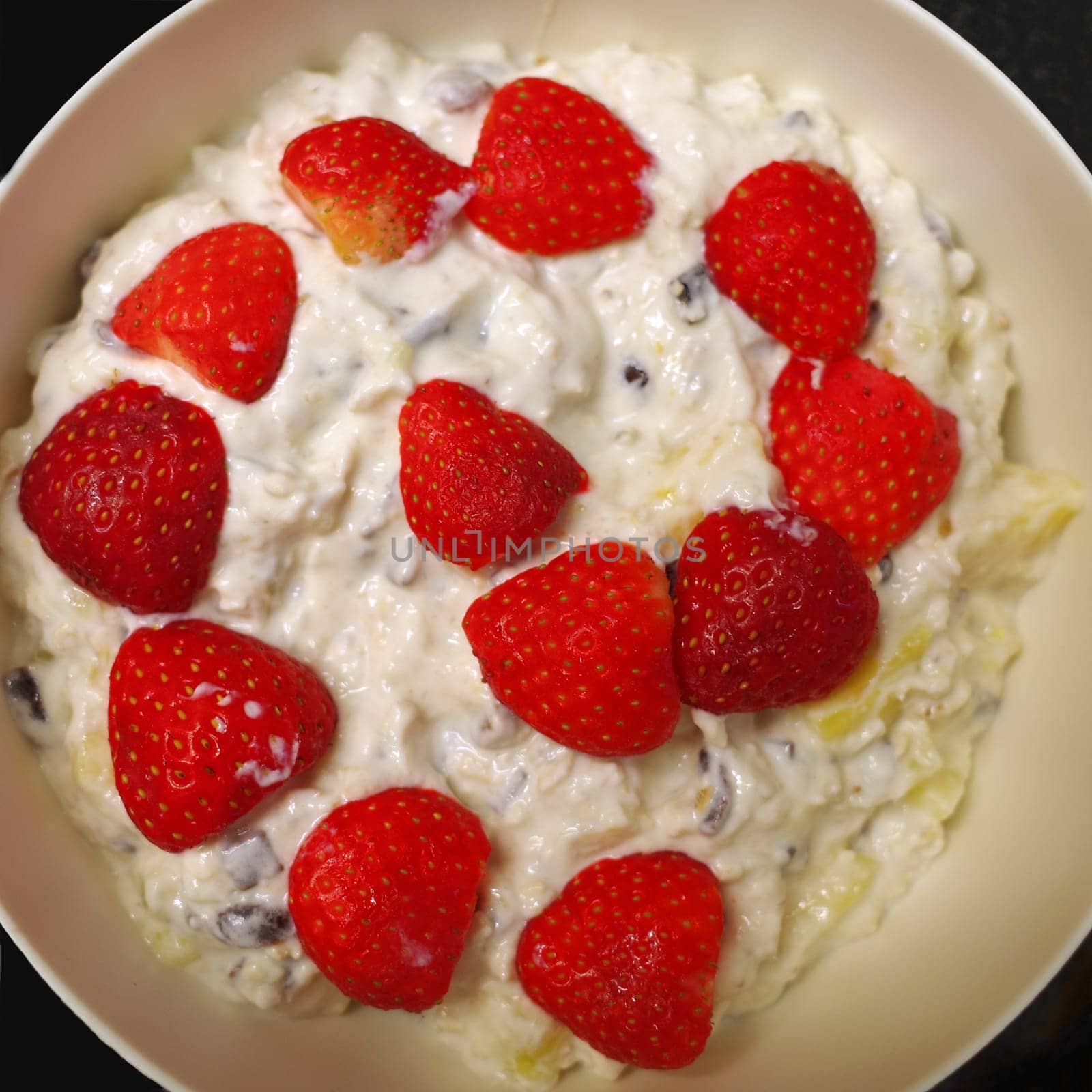 Breakfast made with love. Muesli with yogurt and strawberries on top. The strawberries are placed in a spiral