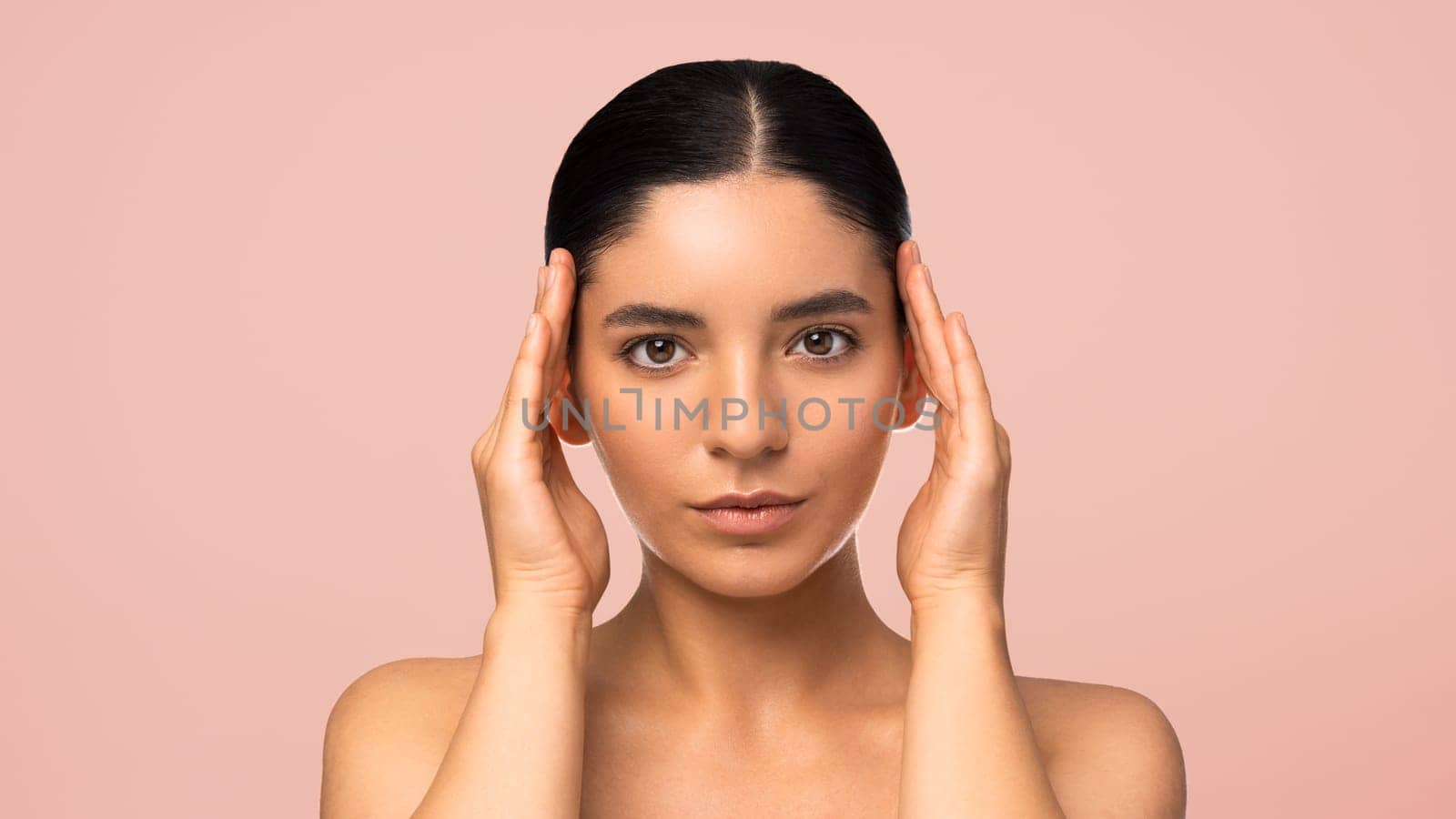 Beauty perfection. Attractive serious woman 25s with perfect skin and symmetrical face holding her hands next to head full face portrait.
