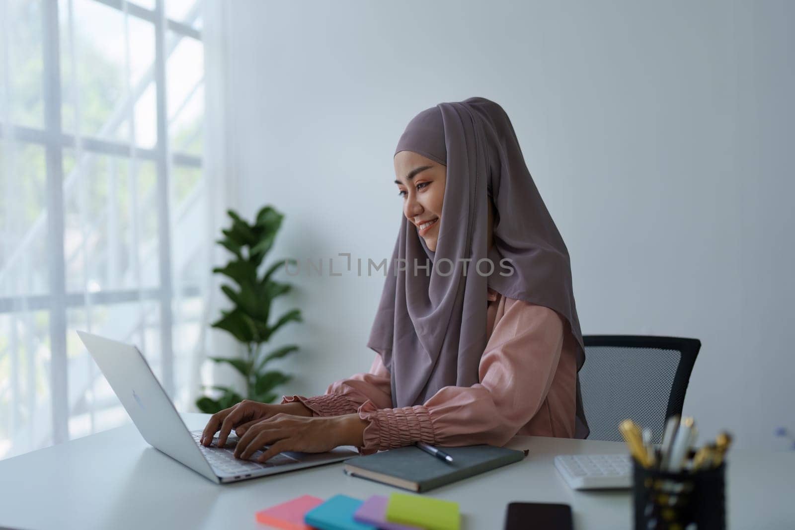Muslim woman manager, lawyer or company employee holding accounting bookkeeping documents checking financial data or marketing report working in office with laptop. Paperwork management.