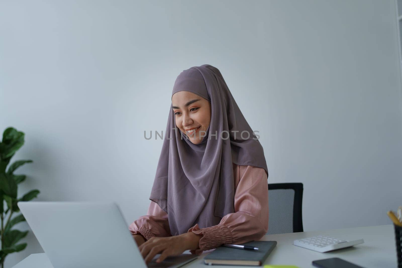Muslim woman manager, lawyer or company employee holding accounting bookkeeping documents checking financial data or marketing report working in office with laptop. Paperwork management by Manastrong