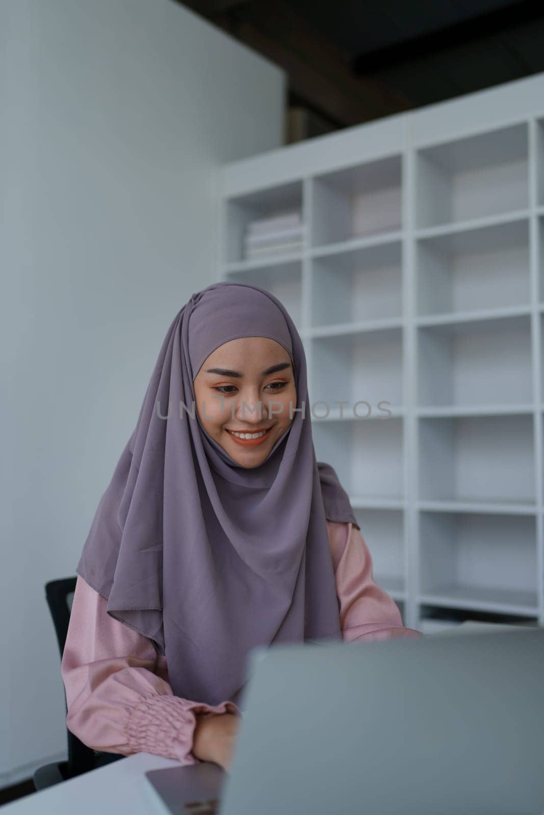 Muslim woman manager, lawyer or company employee holding accounting bookkeeping documents checking financial data or marketing report working in office with laptop. Paperwork management by Manastrong