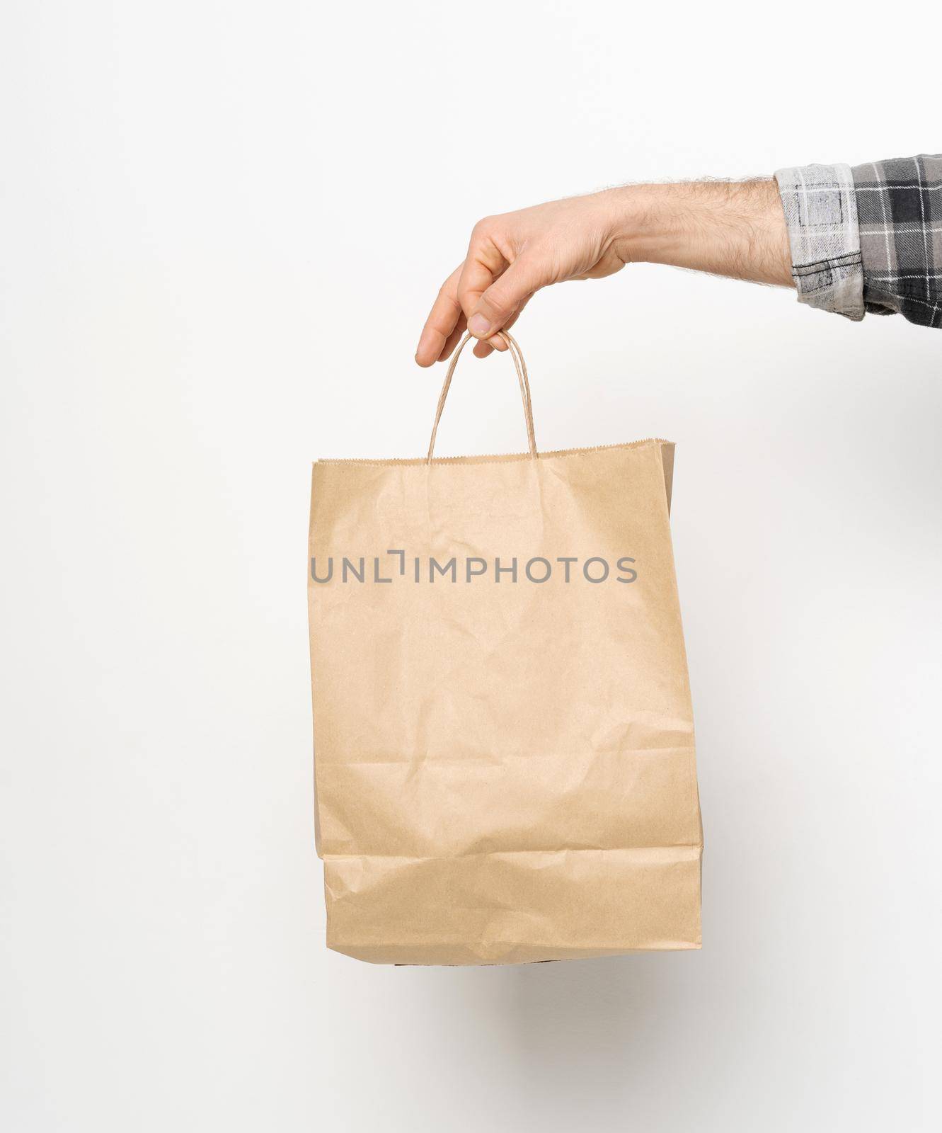 Man hand in plaid shirt twisted sleeve hand holding brown paper bag isolated on white background. Delivery concept. Paper bag for takeaway food. Delivery carrying by LipikStockMedia