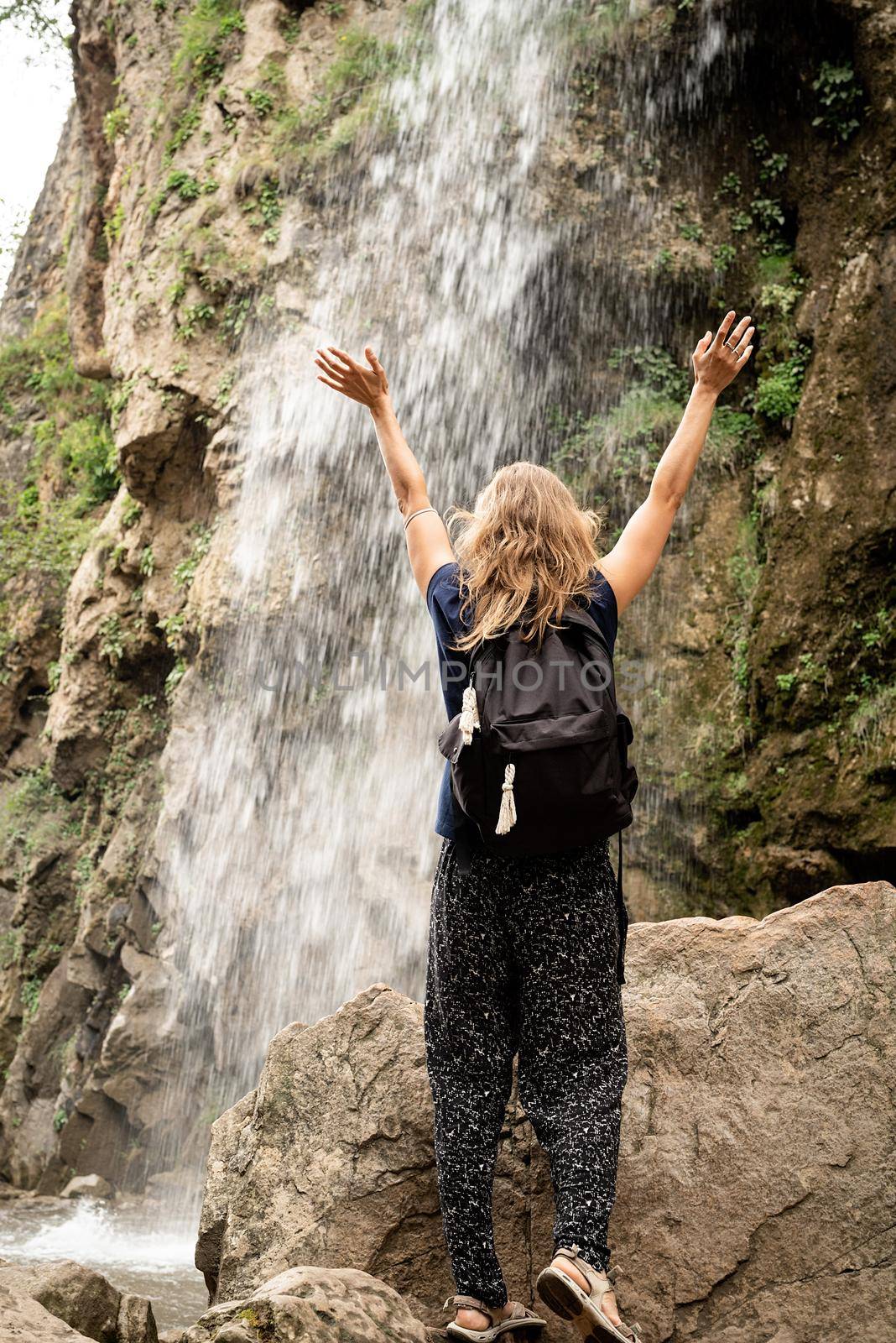Woman standing on bridge looking at the Beautiful mountain waterfall by Desperada