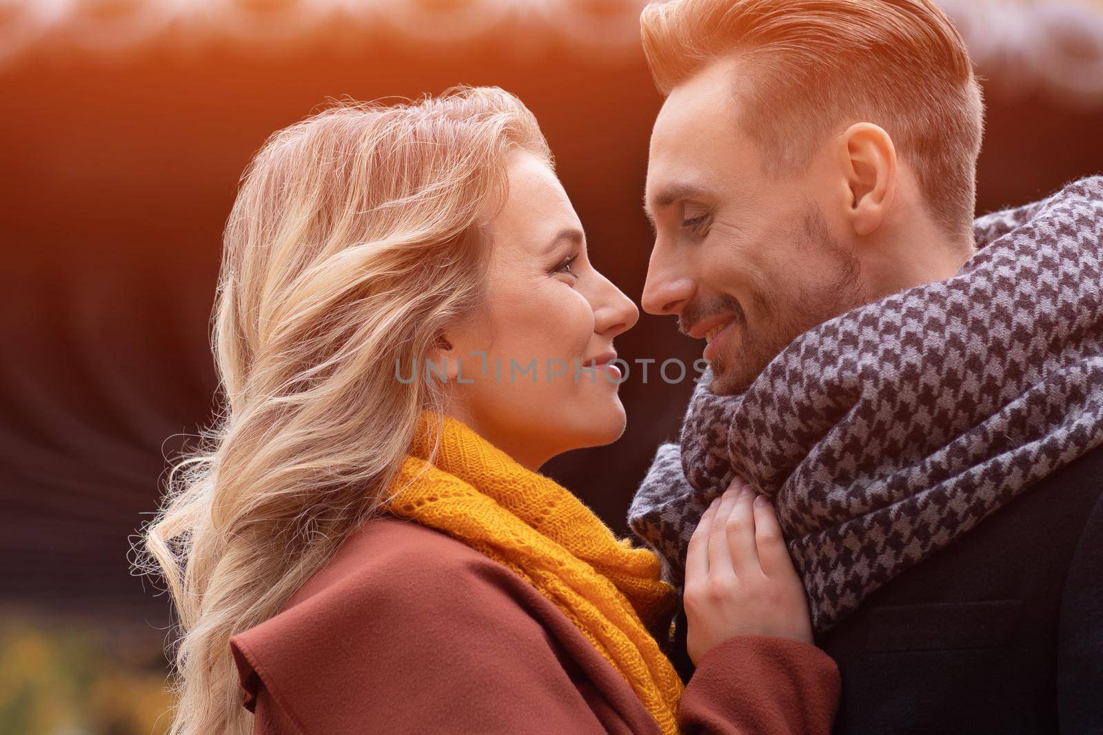 Super close up of kissing young couple. Husband and a wife hugged smile looking at each other in the autumn park. Outdoor shot of a young couple in love by LipikStockMedia