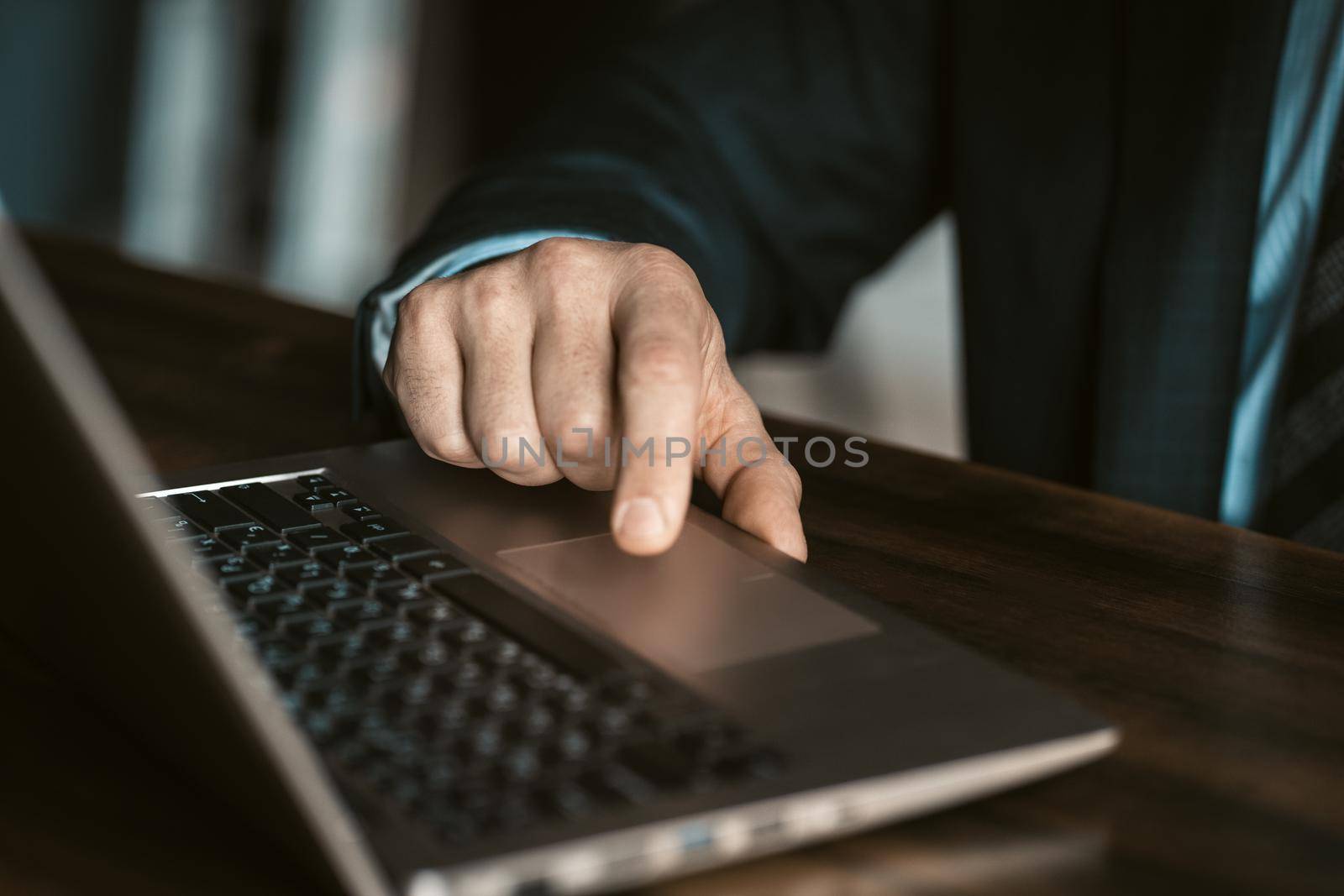 Close up. Hands of a businessman in expensive business suite working on laptop sitting at the modern office. Man working on laptop in office by LipikStockMedia