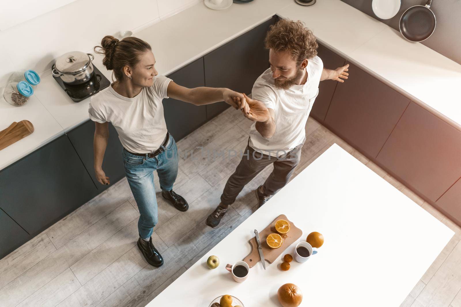 Top view. Young couple dancing in kitchen wearing casual clothes while cooking together at home in love having fun. Love, family, happiness concept.