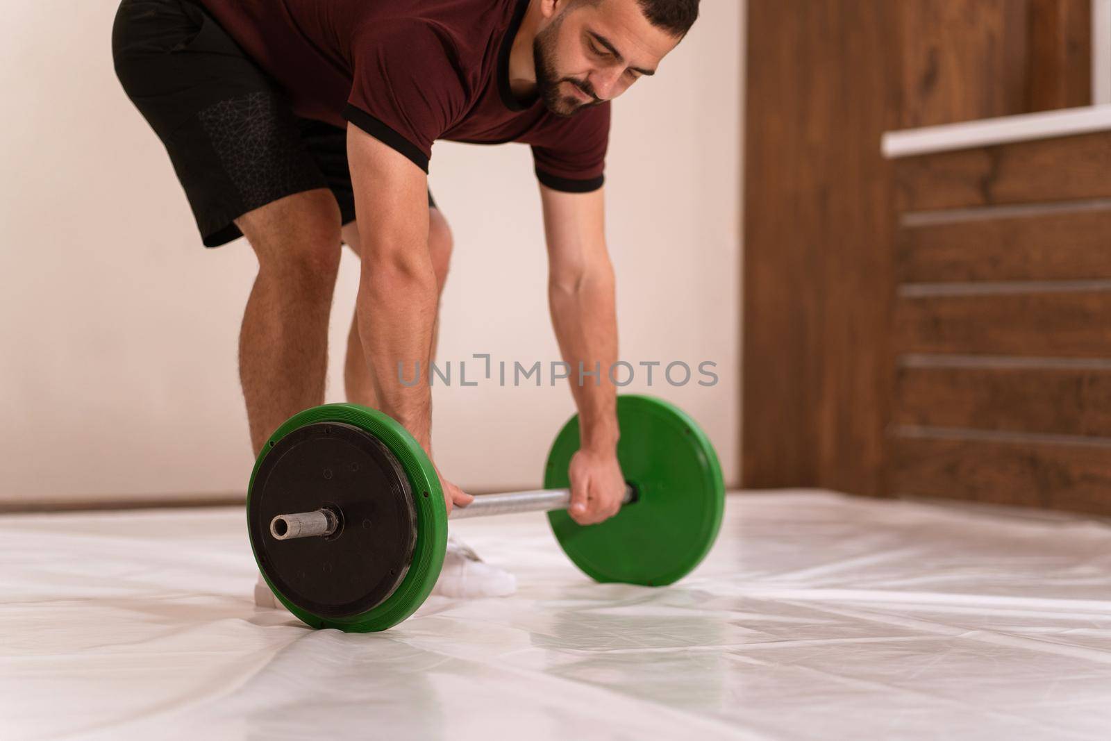 Gripping a barbell young man standing gripped a black and green weight set, equipment for weight training concept. Weight loss, healthy lifestyle concept. Sports equipment for training.