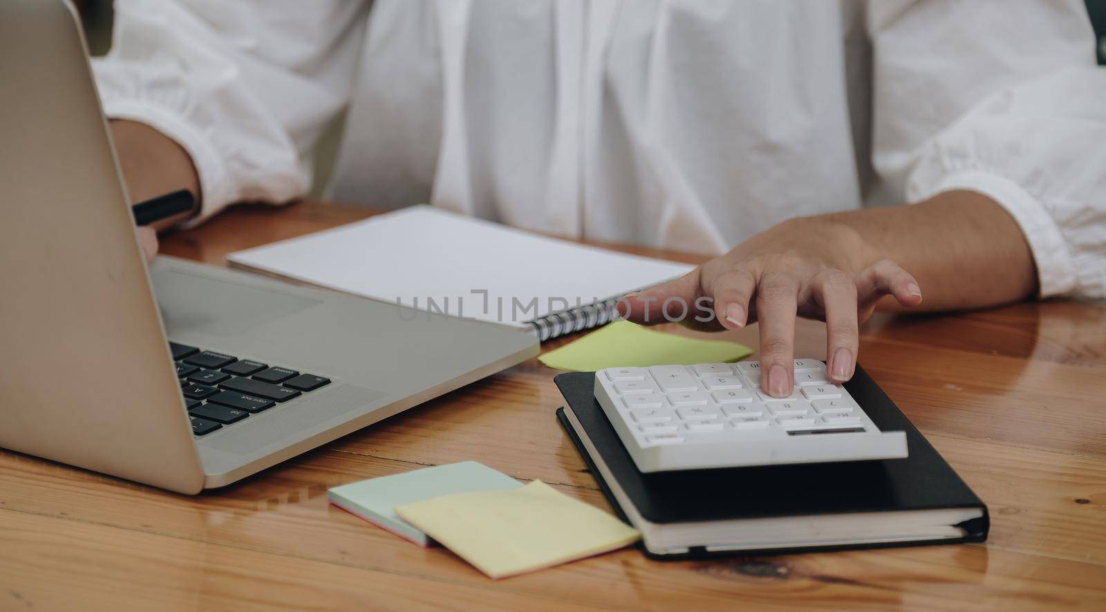 Close up accountant working on desk using calculator and laptop computer for calculate finance report in office. by nateemee