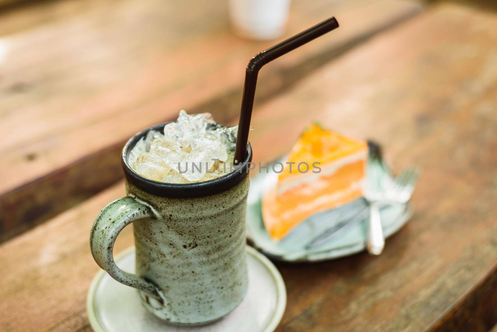 orange cake with ice coffee on wood table